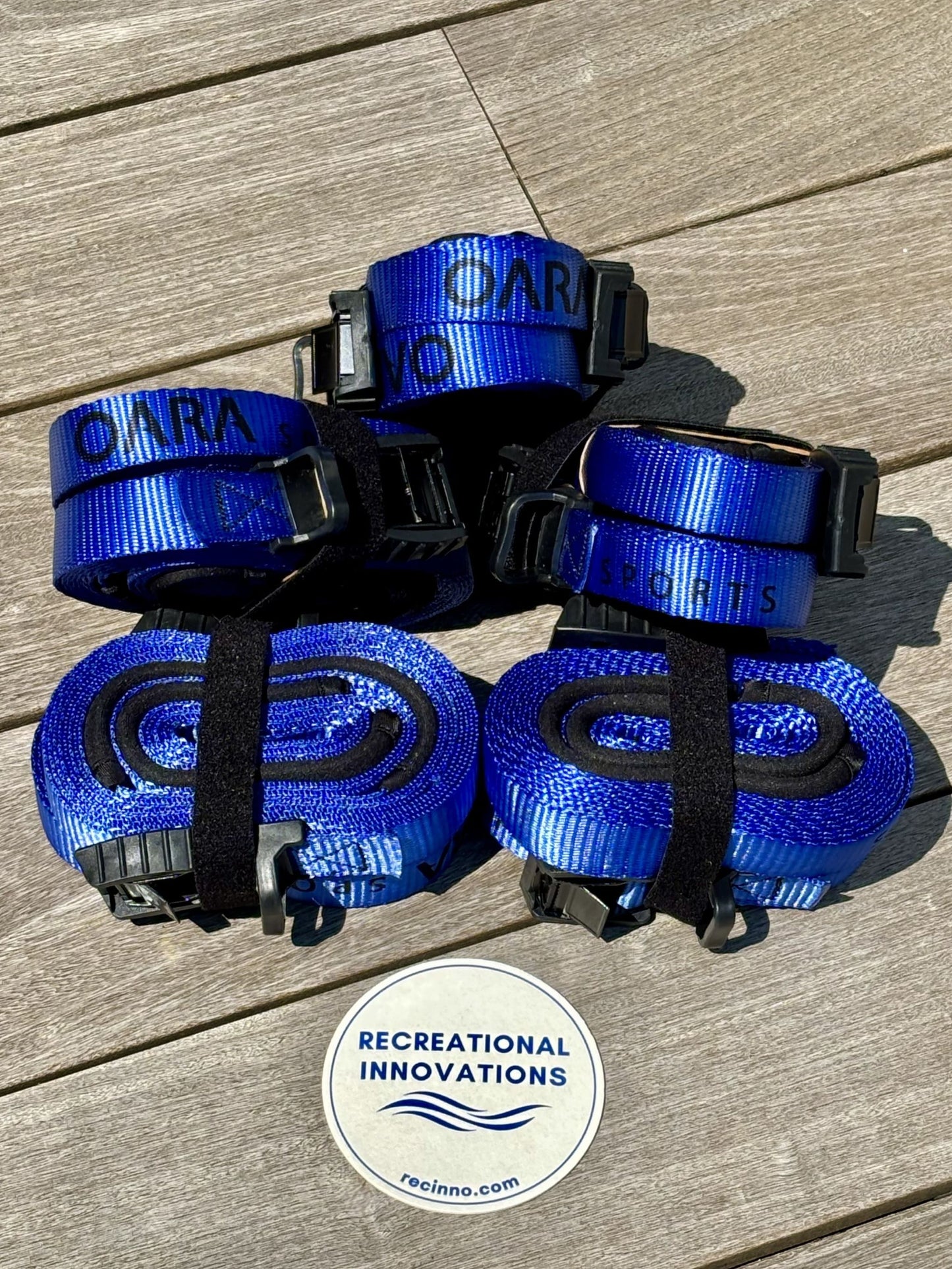 Protective Cam Strap set sitting on the dock. Features neoprene protectors and rubber buckle covers. Order from Recreational Innovations